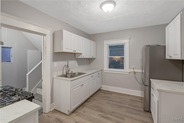 kitchen with sink, light wood-type flooring, and white cabinets