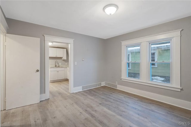 empty room featuring sink and light hardwood / wood-style floors