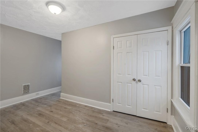 unfurnished bedroom with a closet and light hardwood / wood-style flooring