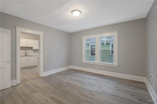 spare room featuring sink and light wood-type flooring