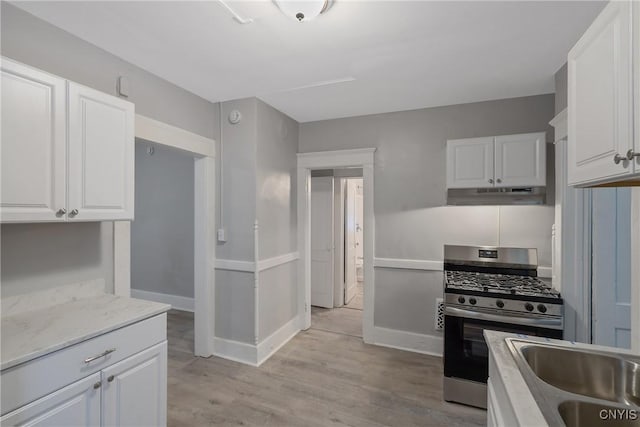 kitchen featuring sink, light stone countertops, stainless steel gas stove, and white cabinetry