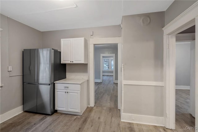 kitchen with white cabinets, stainless steel fridge, and light hardwood / wood-style flooring