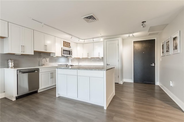 kitchen with dark wood-type flooring, a center island, stainless steel appliances, tasteful backsplash, and white cabinets