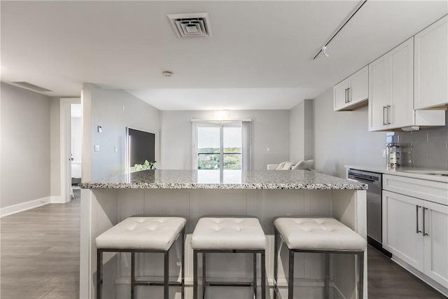 kitchen with dishwasher, a center island, track lighting, white cabinetry, and a breakfast bar area