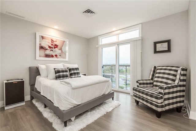 bedroom featuring access to outside, dark wood-type flooring, and a wall of windows