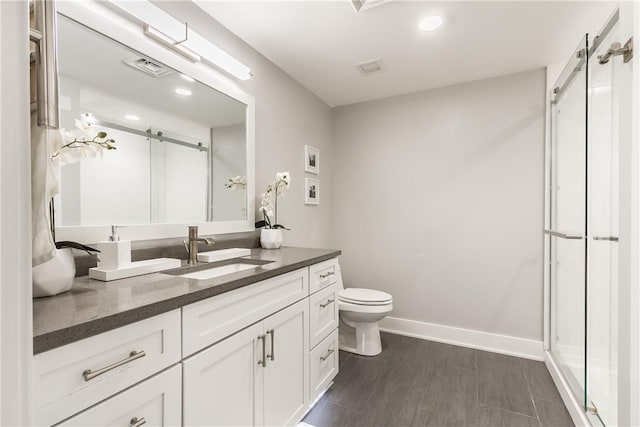 bathroom featuring toilet, a shower with door, and vanity