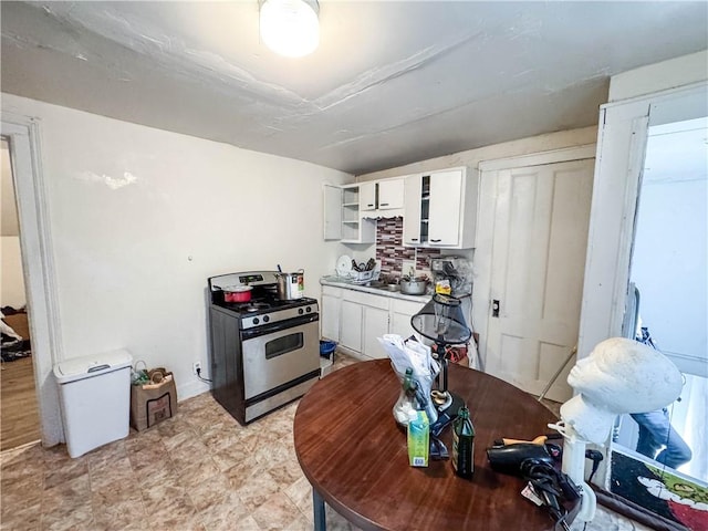 kitchen featuring white cabinets, stainless steel gas stove, and backsplash