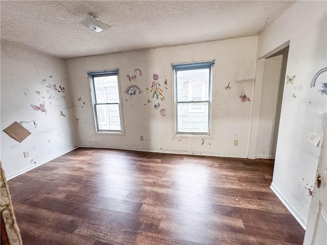 empty room featuring a textured ceiling, dark wood-type flooring, and a healthy amount of sunlight