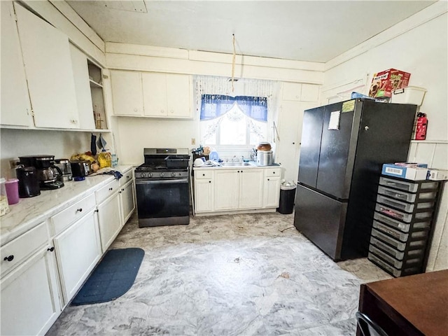 kitchen featuring black fridge, stainless steel range with gas cooktop, and white cabinets