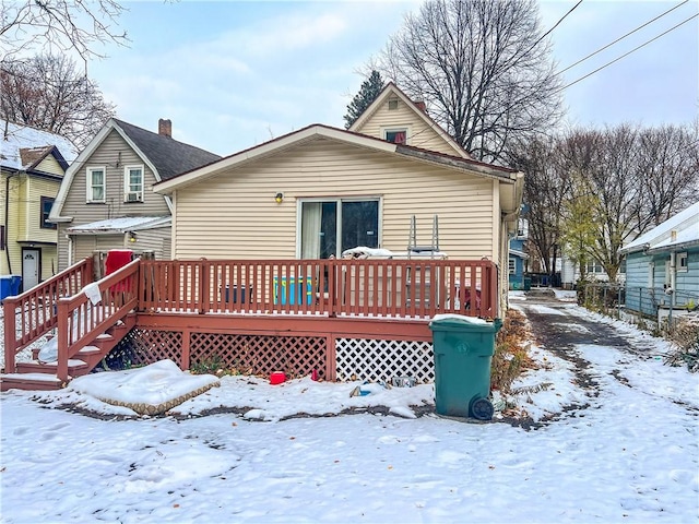 snow covered house with a wooden deck