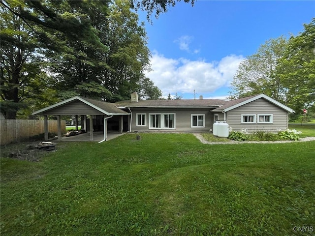 back of property with a patio area, a lawn, and a carport