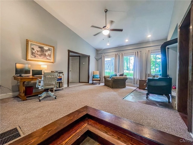 office with ceiling fan, vaulted ceiling, carpet, and a wood stove