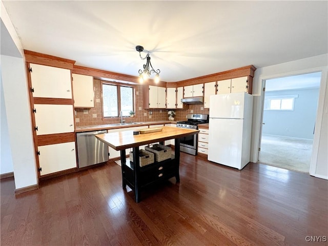 kitchen with appliances with stainless steel finishes, a healthy amount of sunlight, pendant lighting, white cabinetry, and tasteful backsplash