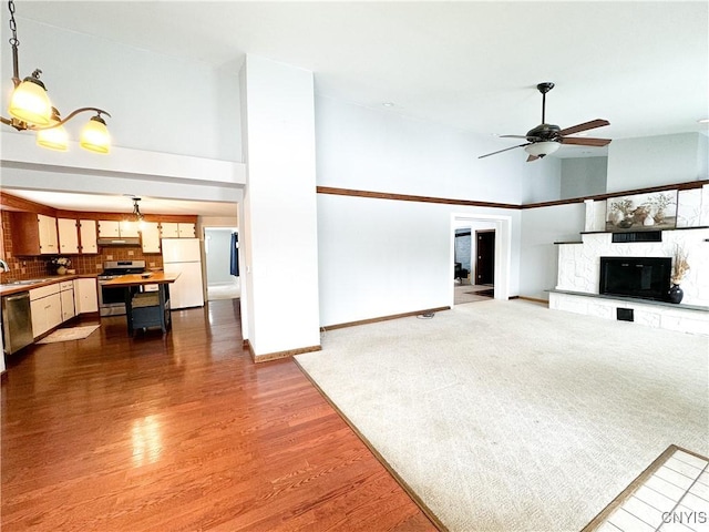 living room featuring sink, wood-type flooring, ceiling fan, and a stone fireplace