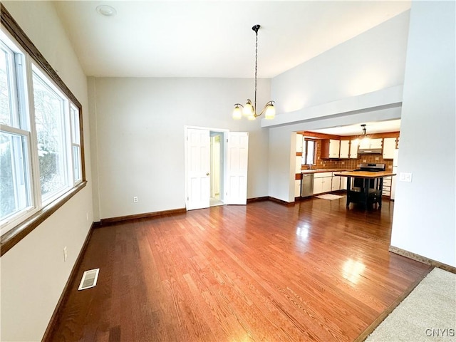 unfurnished living room featuring lofted ceiling, a chandelier, and hardwood / wood-style flooring