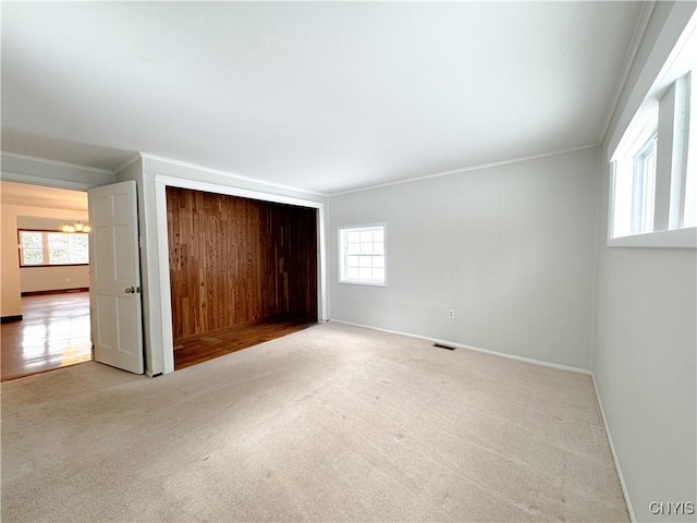 unfurnished bedroom featuring multiple windows, light carpet, and ornamental molding