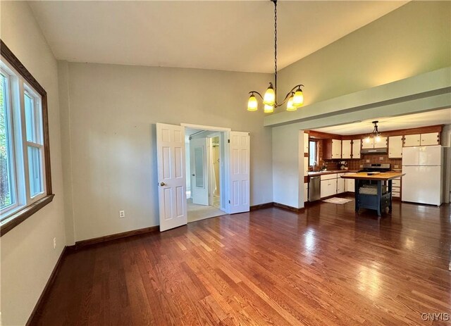5902 N Rd, Owasco, NY 13021 - unfurnished living room featuring a chandelier, baseboards, dark wood finished floors, and a towering ceiling