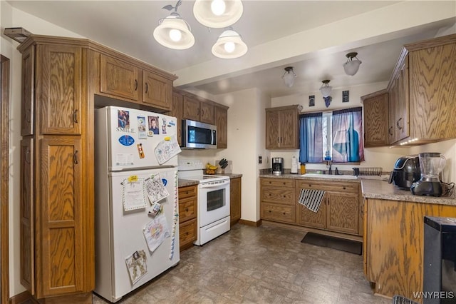 kitchen with white appliances, pendant lighting, and sink