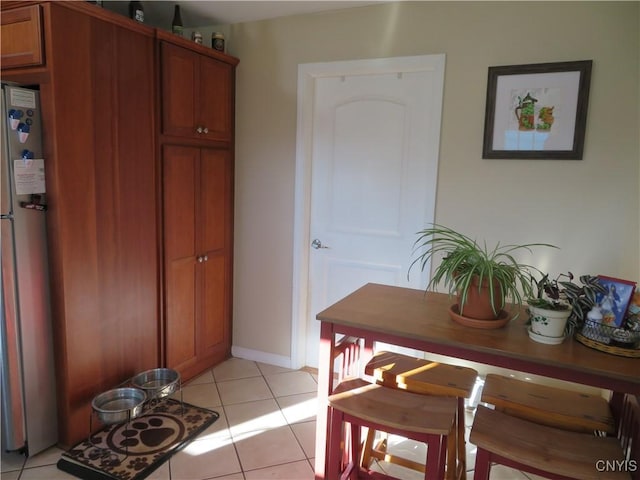 interior space featuring stainless steel fridge and light tile patterned flooring