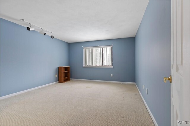 empty room featuring track lighting and light carpet