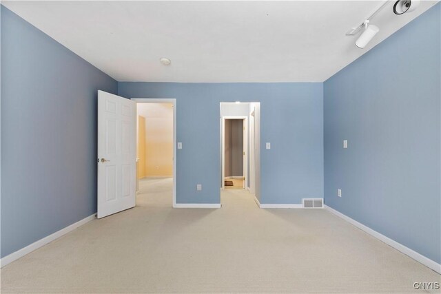 spare room featuring rail lighting and light carpet