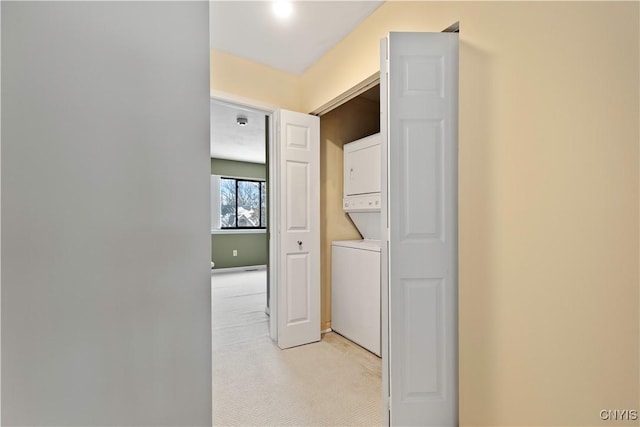 corridor with stacked washer and clothes dryer and light colored carpet