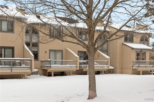 snow covered rear of property featuring a wooden deck