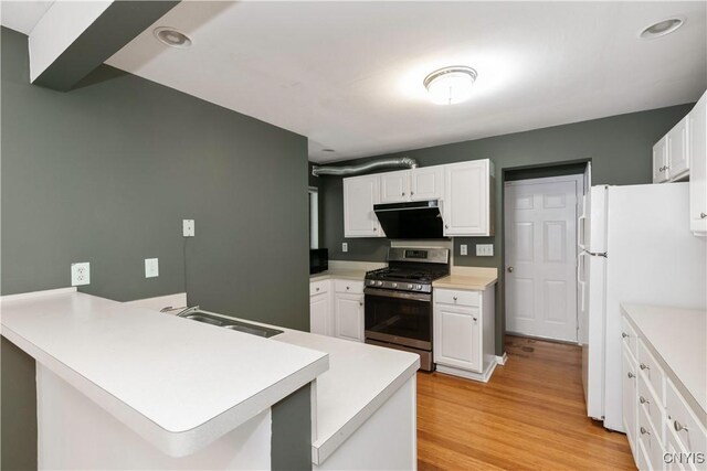 kitchen featuring stainless steel range with gas stovetop, white cabinetry, and kitchen peninsula