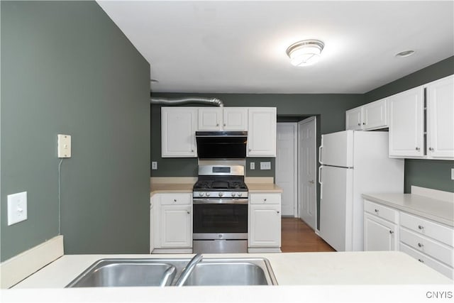 kitchen featuring sink, white fridge, gas range, and white cabinets