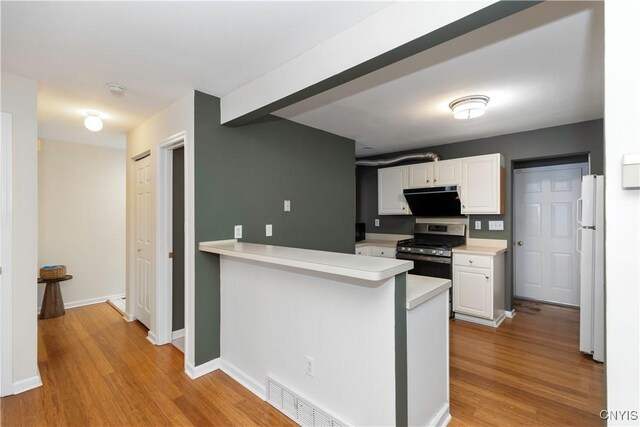 kitchen featuring kitchen peninsula, white cabinets, stainless steel gas range, and ventilation hood