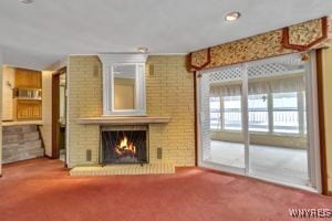 unfurnished living room with a brick fireplace, a wealth of natural light, and carpet flooring