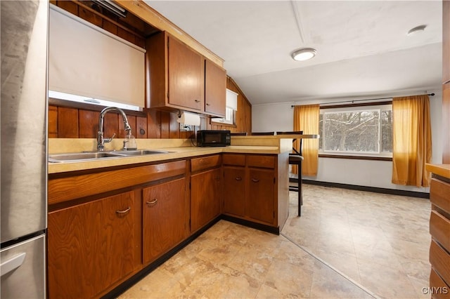 kitchen featuring sink, kitchen peninsula, and stainless steel refrigerator