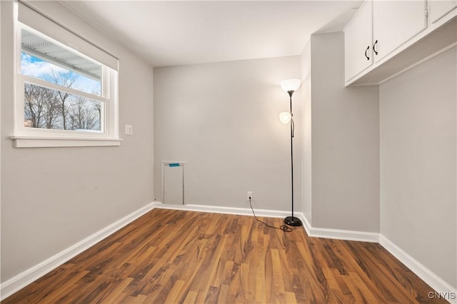 laundry area featuring dark wood-type flooring and cabinets