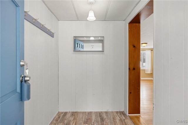 hallway with light hardwood / wood-style flooring and wood walls