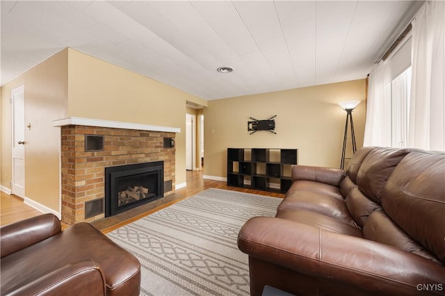 living room with light hardwood / wood-style floors and a brick fireplace