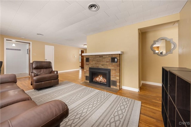 living room featuring a brick fireplace and hardwood / wood-style flooring