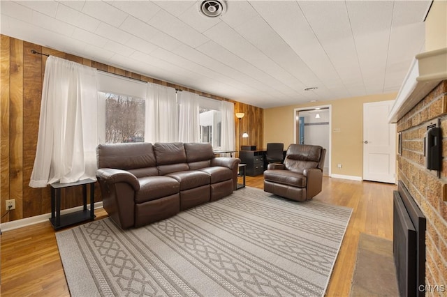 living room featuring light hardwood / wood-style flooring, wooden walls, and a fireplace