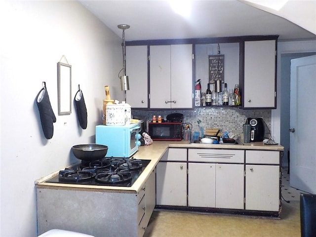 kitchen with tasteful backsplash, decorative light fixtures, black gas stovetop, and gray cabinetry