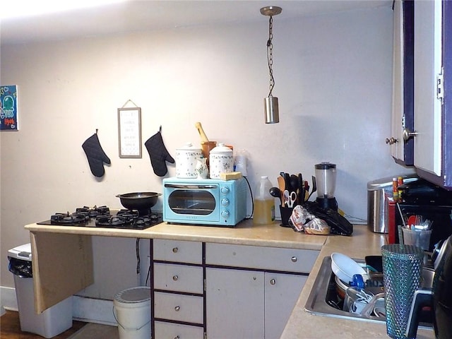 kitchen featuring white cabinetry, decorative light fixtures, and black gas stovetop