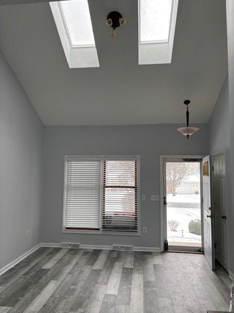 foyer entrance featuring high vaulted ceiling, a skylight, and hardwood / wood-style flooring