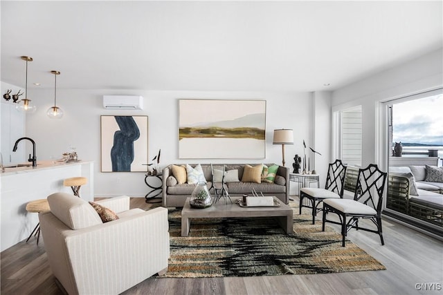 living room featuring a wall mounted AC, sink, and hardwood / wood-style floors