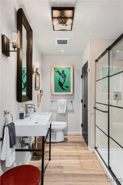 bathroom featuring wood-type flooring, an enclosed shower, and toilet