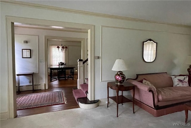 living room with a notable chandelier, baseboard heating, and crown molding