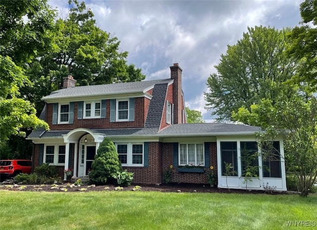 view of front of house with a sunroom and a front yard