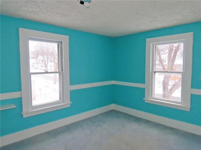 unfurnished room with a textured ceiling, concrete floors, and plenty of natural light