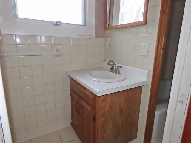 bathroom with vanity, tile patterned flooring, tile walls, and a wealth of natural light