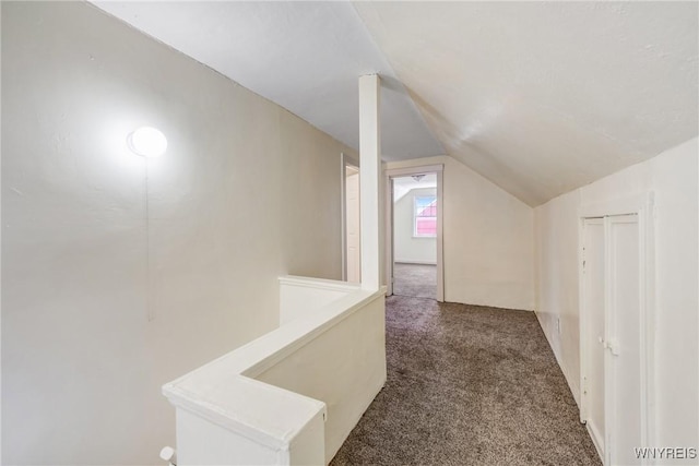 hallway featuring lofted ceiling and dark carpet