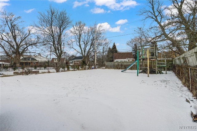 snowy yard featuring a playground