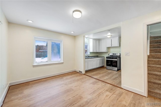 kitchen with white cabinets, gas range, and light hardwood / wood-style floors