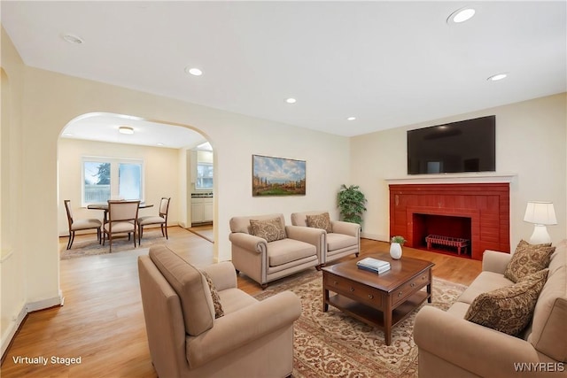 living room with a brick fireplace and light hardwood / wood-style floors